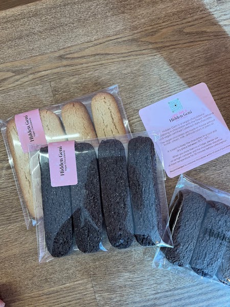 Packages of artisanal cookies and a card from Hidden Gem chocolate shop displayed on a wooden surface