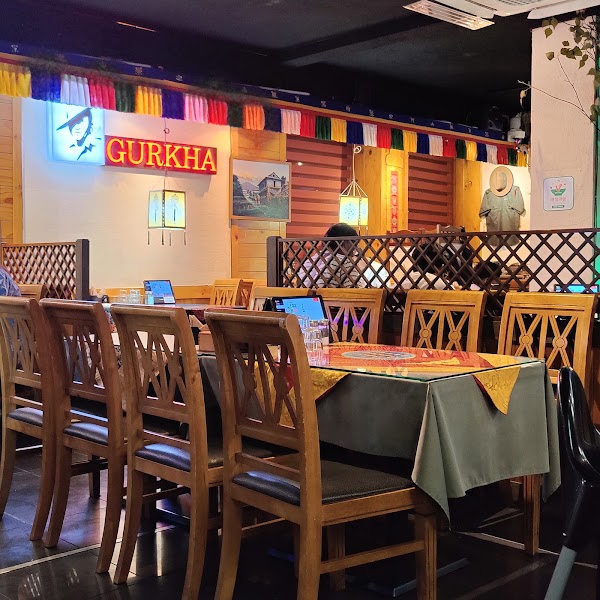 Interior of Gurkha Indian Restaurant with wooden tables, chairs, and traditional prayer flags
