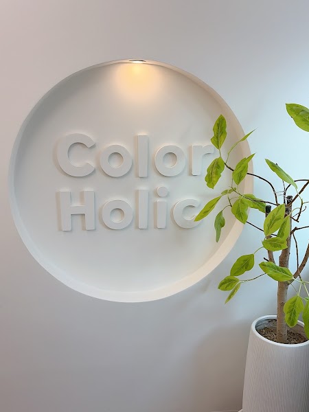 3D logo for Color Holic mounted on a circular recessed wall feature with a nearby indoor plant