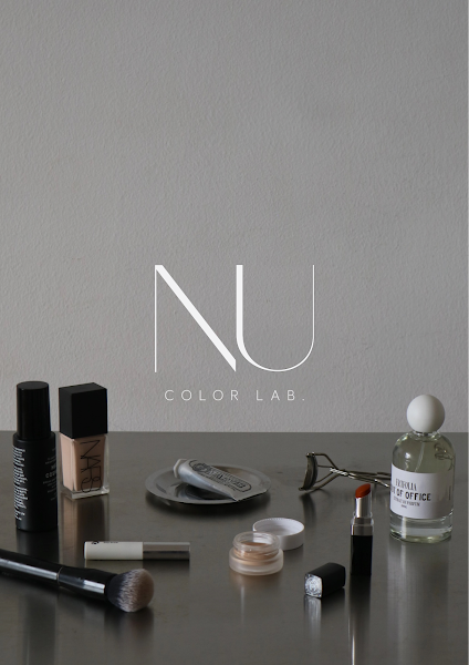 Logo of NU COLOR LAB displayed above collection of makeup products and perfume bottle on metallic surface