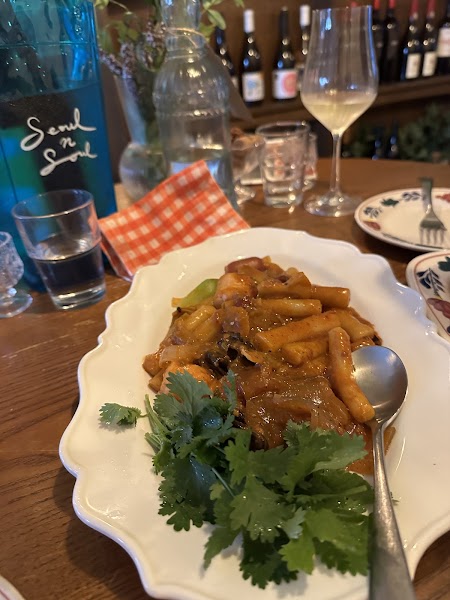 Saucy spicy rice cakes piled high with fresh cilantro served on a scalloped plate
