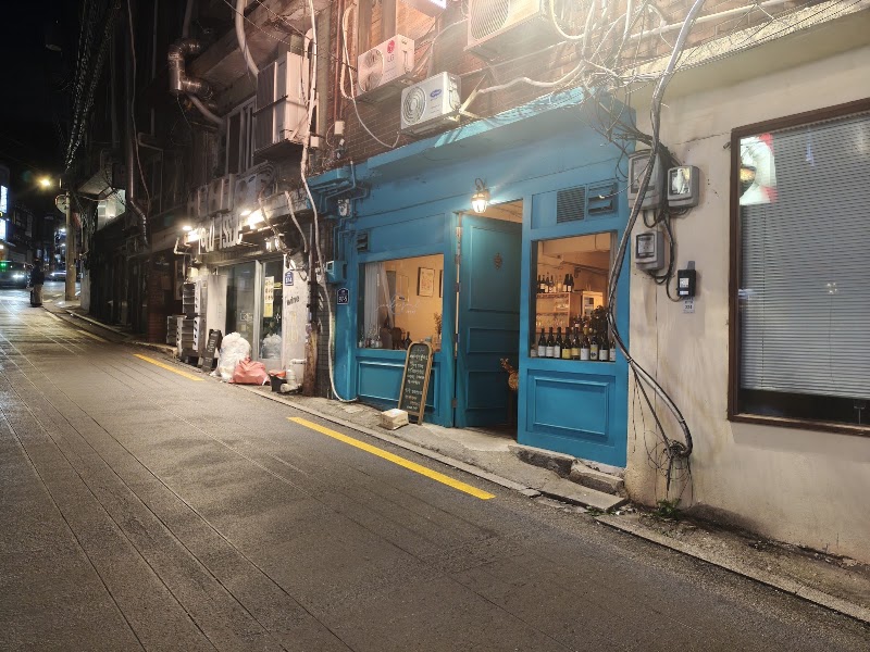 Turquoise wooden storefront of Seoul'n'Soul glowing on a quiet evening street