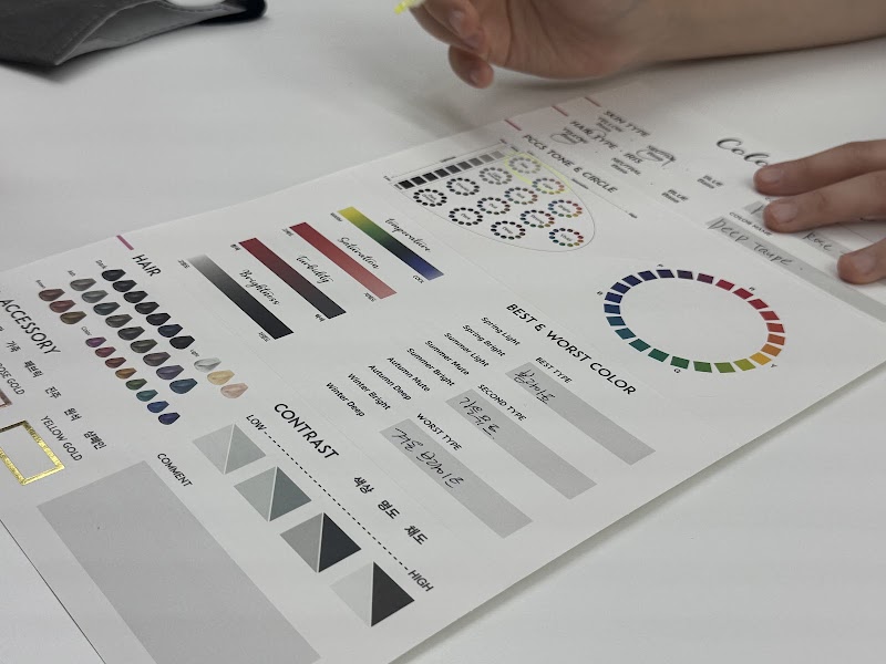A personal color analysis chart on a white desk with handwritten Korean notes and a marker pen in hand