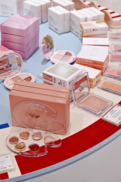A selection of colorful cosmetic palettes and makeup products arranged on curved display table