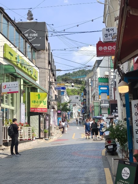 A narrow street in Seoul lined with restaurants leading toward Kampungku