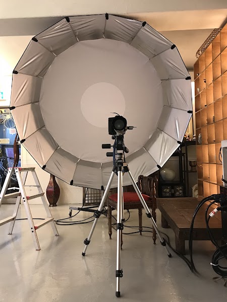 A professional photography studio setup with a large circular light modifier on a tripod-mounted camera.