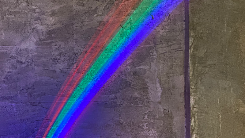 Atmospheric prismatic spectrum of light reflecting on dark textured wall