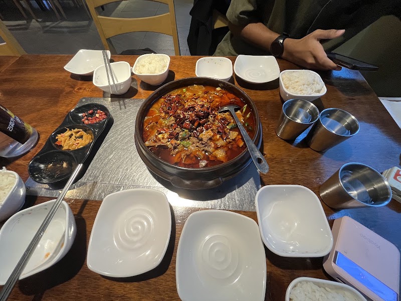 Table spread featuring spicy stew and noodle accompaniments