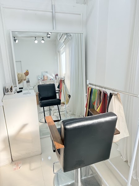 Minimalist studio interior with large mirror, salon chair, and fabric draping racks