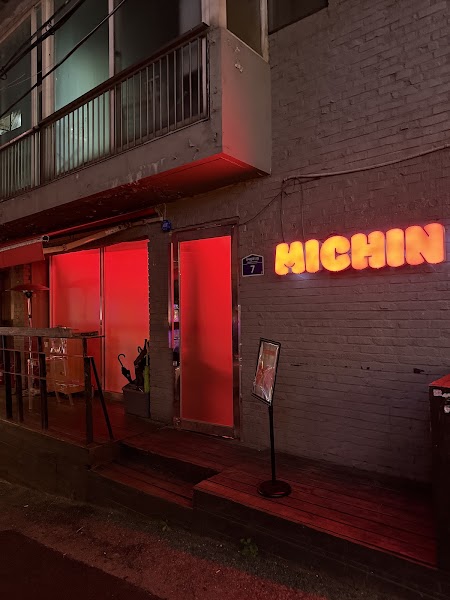 Exterior night view of MICHIN bar in Seoul with a glowing orange neon sign on a brick wall