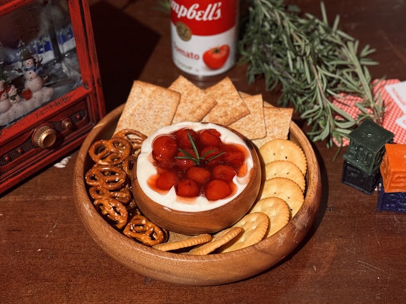 Wooden bowl of crackers, pretzels, and savory berry-topped cream dip