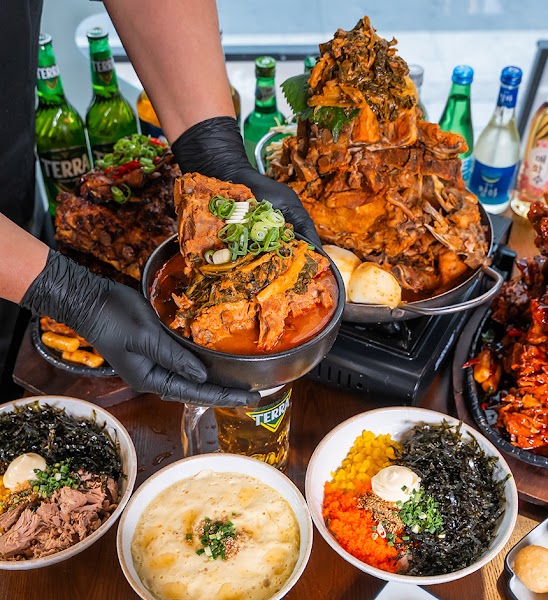 Bowl of spicy gamjatang pork rib soup with table dishes in background