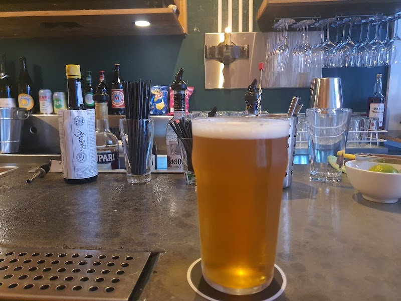 Fresh beer pour on a stone counter at Bard's Apothecary with backdrop of liquor shelves