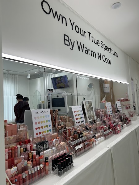 Interior of Warm N Cool color analysis studio featuring cosmetic displays and a large mirror with branding.