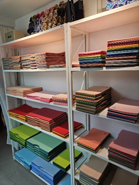 White metal shelving unit filled with organized stacks of colorful fabric swatches for color analysis