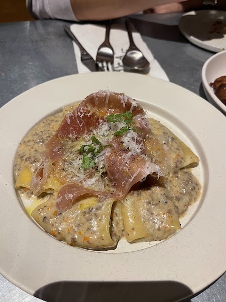 Plate of ribbon pappardelle pasta in creamy mushroom sauce with prosciutto and grated cheese
