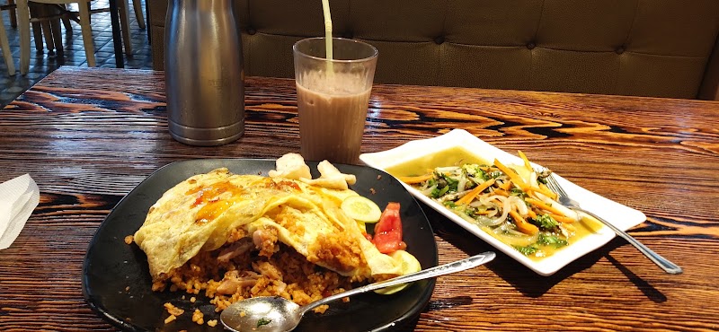 A plate of fried rice with egg and side dishes on a restaurant table