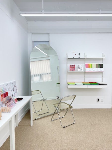 Interior of a modern, minimalist color consultation studio with an arched floor mirror and color palette display.