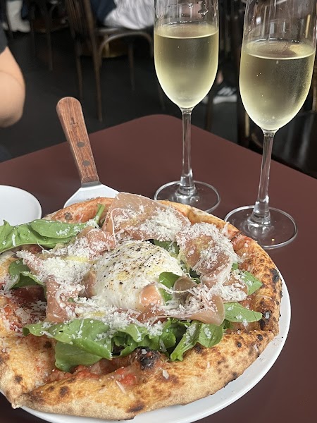Table spread with artisan pizza and glasses of sparkling natural wine
