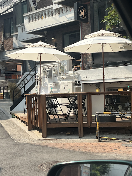 Outdoor terrace seating with white umbrellas on Haebangchon alley deck
