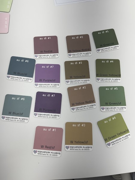 A collection of square color sample cards labeled with season and hue codes arranged on a white table.