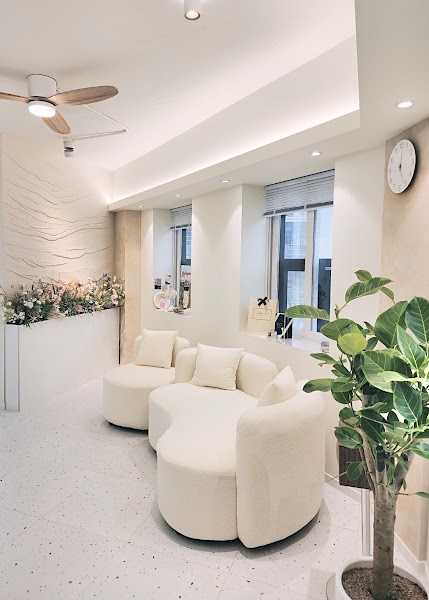 A clean, bright waiting room in a personal color analysis studio with cream-colored curved sofas and lush indoor greenery