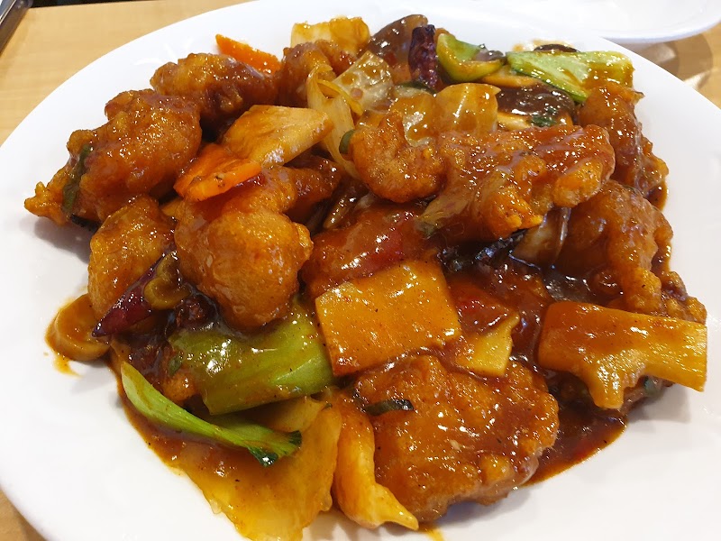 A close-up shot of a plate of stir-fried meat with vegetables in a glossy brown sauce at a Chinese restaurant.