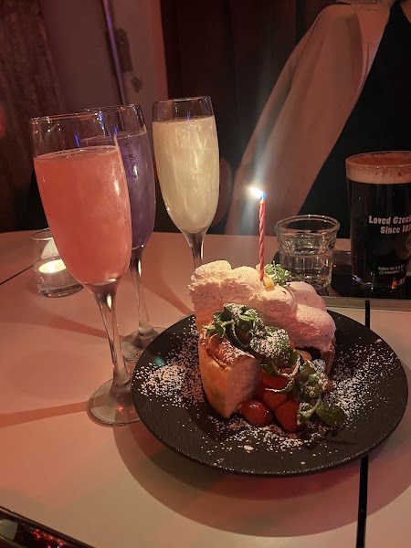 Sparkling celebration drinks and a small dessert with a lit candle on a table