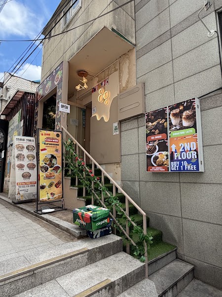 Exterior entrance of Bali Holiday Halal Restaurant in Seoul with food menu signs and staircase