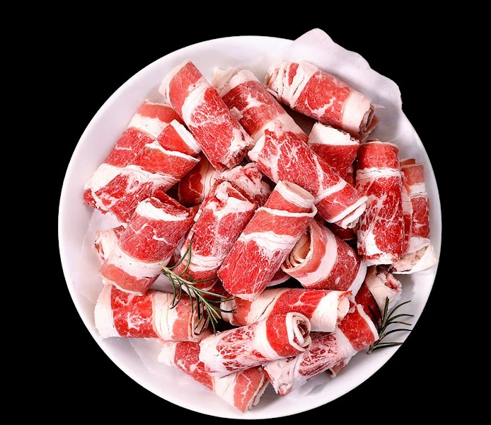 Rolled thinly sliced raw beef on a serving plate ready for tabletop barbecue