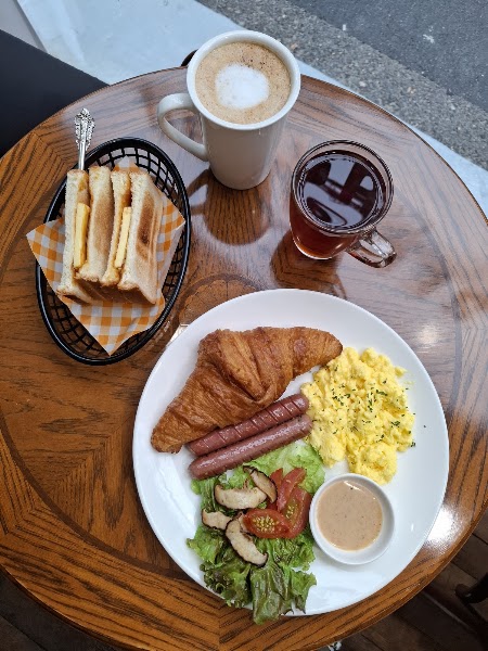 Hearty Malaysian breakfast plate with croissant, eggs, and sausage