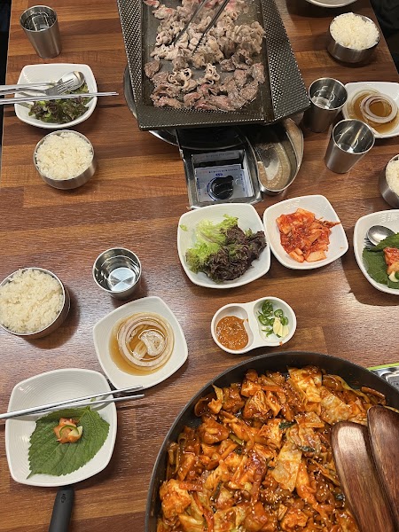 Full tabletop feast with rice bowls, Korean side dishes, and grilled meats