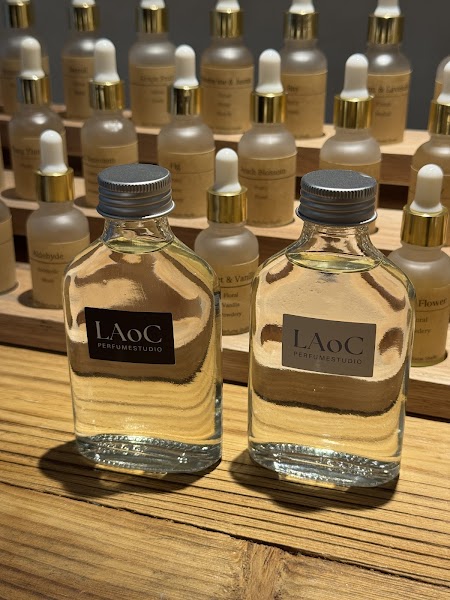 Two perfume bottles with LAoC labels on a wooden display shelf in a perfume studio.