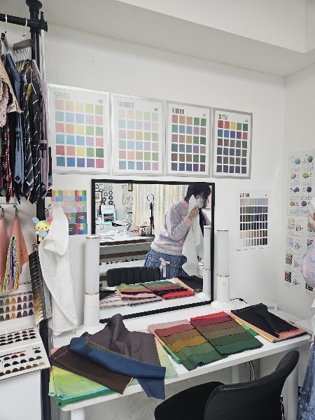 Interior of a personal color consultation studio featuring fabric swatches and seasonal color charts on a white desk.