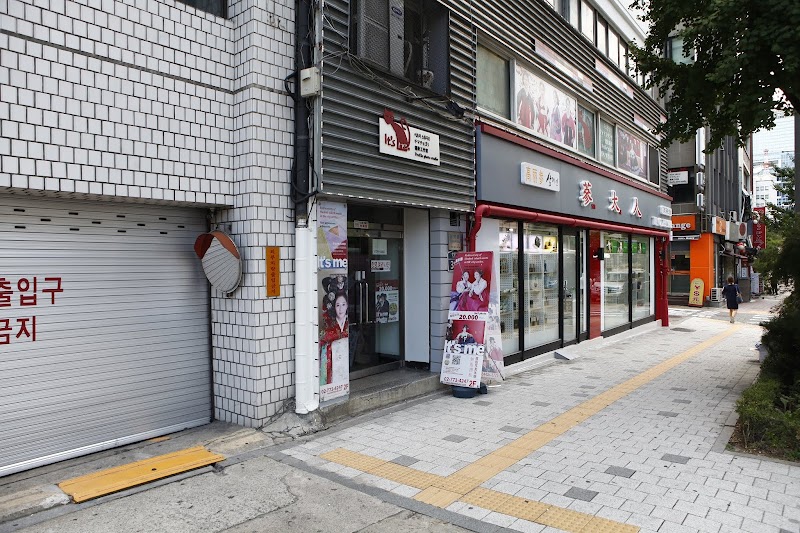 Street level view of It's Me Photo Studio storefront in Seoul with brick walls and signage.