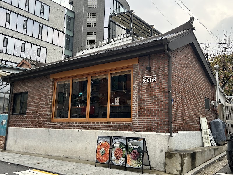 Exterior view of Doyajib Korean BBQ restaurant in Seoul with brick walls, wood-framed windows, and food signage