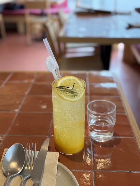 Iced yellow citrus drink garnished with lemon wheel and rosemary sprig