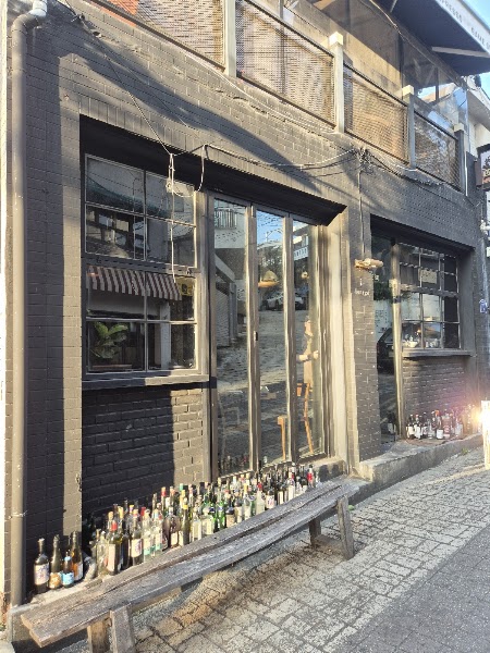 Rustic wooden bench lined with glass wine bottles outside the dark brick storefront