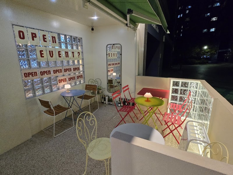 Outdoor patio terrace seating area at night with bistro tables, table lamps, and glass block wall