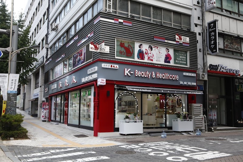 Corner storefront of It's Me Photo Studio and K-Beauty & Healthcare in Seoul with red and gray accents.