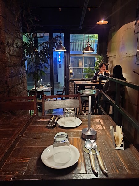 Dim table setting for two with candle-style lamp and glassware looking toward the window