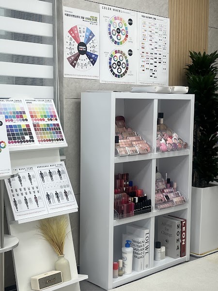 A white storage unit displaying various makeup palettes and lipsticks in a professional color analysis studio.