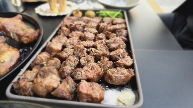 A rectangular plate of seared meat cubes garnished with herbs