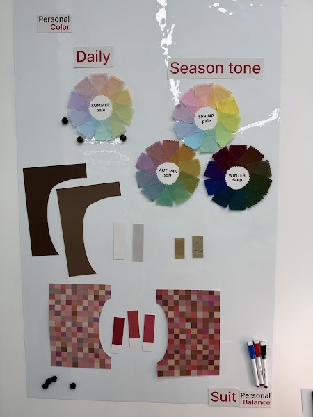 White board displaying personal color season tone charts and fabric swatches at consultant office