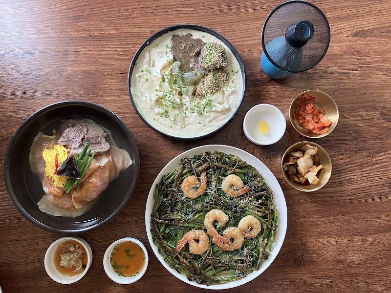 Curated spread of Korean fusion dishes including dumpling soup, creamy noodles, herb shrimp pancake and side dishes