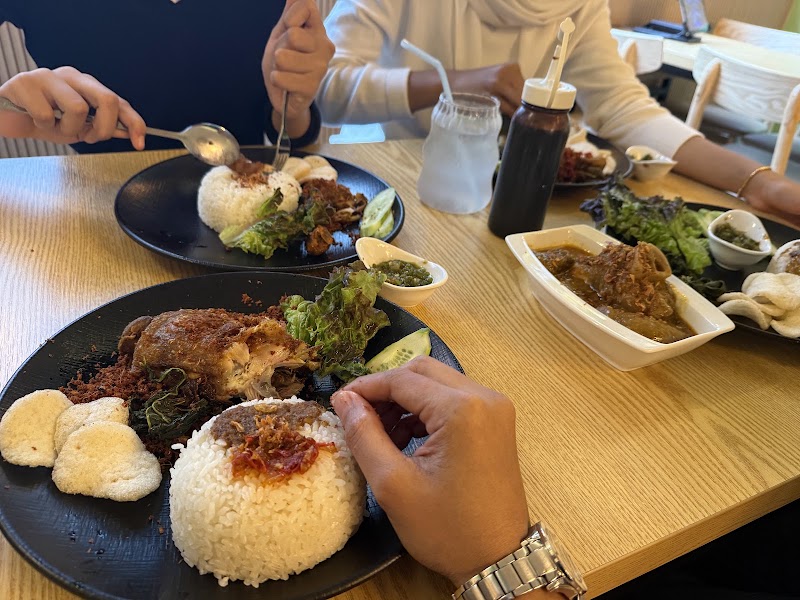 People dining at restaurant table with plates of rice, fried food, and side dishes