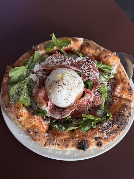 Freshly baked artisan pizza topped with burrata, prosciutto, and arugula