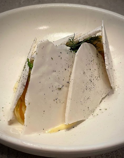 Delicate culinary plate with herb garnishes and crisp white shards