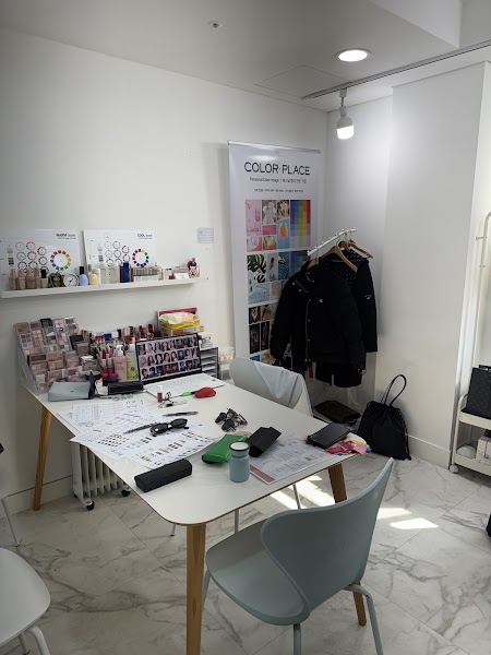 Consultation desk with cosmetic palettes, color charts, laptop, and garment rack