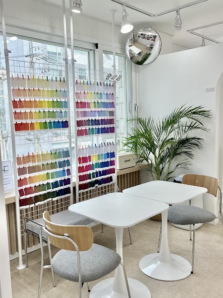 Interior of a color consultation studio featuring wall-mounted color swatch grids, white tables, and minimalist chairs.